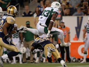 Saskatchewan Roughriders' Jerome Messam (33) jumps over Winnipeg Blue Bombers'  Maurice Leggett during the second half of their CFL football game in Winnipeg August 7, 2014.