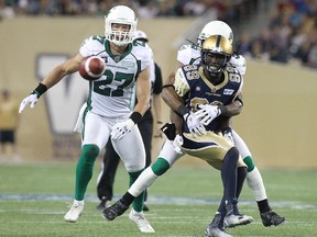 Receiver Clarence Denmark #89 of the Winnipeg Blue Bombers awaits the ball as he is held during action against the Saskatchewan Roughriders looks on in second half action in a CFL game at Investors Group Field on August 7, 2014.