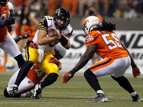 Hamilton Tiger-Cats quarterback Dan LeFevour (13) is tackled by B.C. Lions' linebackers Adam Bighill (44) and Solomon Elimimian (56) on Aug. 8. (Reuters)