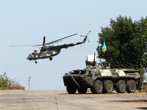 A Ukrainian army helicopter flies near an armored personnel carrier (APC) near Donetsk August 9, 2014.REUTERS/Valentyn Ogirenko