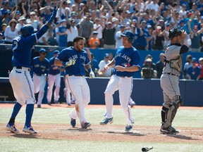 Toronto Blue Jays third baseman Danny Valencia (right) celebrates with left fielder Melky Cabrera (centre) scoring the winning run in the 10th inning against the Detroit Tigers at the Rogers Centre in Toronto, Aug. 9, 2014. (NICK TURCHIARO/USA Today)