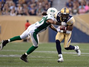 Winnipeg Blue Bombers' Nic Grigsby (right) is tackled by Saskatchewan Roughriders' Rod Williams during the first half of their CFL football game in Winnipeg Aug. 7, 2014.