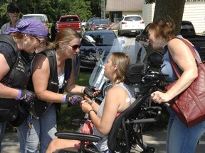 Deb Roswell and Carol Ziemann, members of the Iron Sirens motorcycle group out of Woodstock, present Desiree Gallagher with an 'angel bell' at a fundraiser on Saturday.