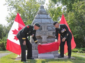Maj-Gen. Dean Milner, left, and Chief Warrant Officer J.M.A. Brideau uncover the new rededication plaque at a ceremony at the 1st Canadian Division cenotaph in the Barriefield Rock Garden on Sunday. In honour of its 100th anniversary, the 1st Canadian Division added a rededication plaque to the memorial. (Julia McKay/The Whig-Standard)