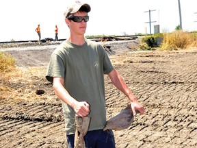 Tim Crombach holds pieces of scrap metal left behind in a family field after the dismantling of rail cars following a derailment east of Gananoque last week. The family is looking for compensation from CN for land damage caused during the cleanup (NICK GARDINER/The Recorder and Times).