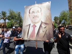 Iraqis carry a portrait of Iraqi Prime Minister Nuri al-Maliki as they march in support of him in Baghdad, August 11, 2014. Iraqi Prime Minister Nuri al-Maliki was battling to keep his job on Monday, deploying forces across Baghdad as some parliamentary allies sought a replacement and the United States warned him not to obstruct efforts to form a new government.  REUTERS/Ahmed Saad