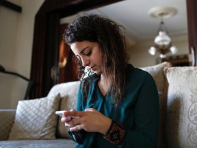 Farah Baker, 16, uses her phone to tweet in her family's home in Gaza City, Aug. 10, 2014.   REUTERS/Siegfried Modola