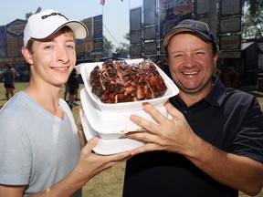 Trevor and Michael Lunney hold their three orders of freshly-cooked pork ribs Sunday at Ribfest.