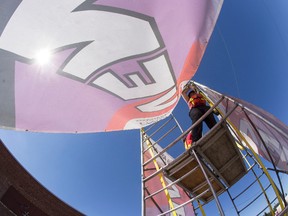 Site crew members Sammy Perrin (centre) and Glenna Schowalter (back) put up signs on scaffolding at the 2014 Edmonton International Fringe Theatre Festival site in Edmonton, Alta., on Monday, Aug. 11, 2014. The 33rd annual festival runs from Aug. 14 to 24. Ian Kucerak/Edmonton Sun/QMI Agency