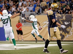 Bombers quarterback Drew Willy (right) walks off the field after giving up a interception touchdown to Roughriders' Terrell Maze (centre) during second half CFL action in Winnipeg on Aug. 7, 2014. (Fred Greenslade/Reuters)
