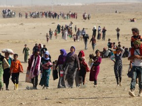 Displaced people from the minority Yazidi sect, fleeing violence from forces loyal to the Islamic State in Sinjar town, walk towards the Syrian border, on the outskirts of Sinjar mountain, near the Syrian border town of Elierbeh of Al-Hasakah Governorate August 11, 2014. REUTERS/Rodi Said