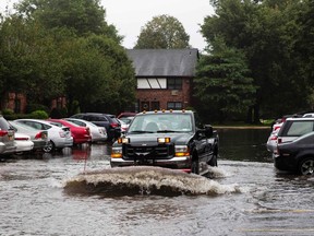 Adelmo Perez uses a truck and plow to push water out of a housing complex parking lot in North Babylon, New York August 13, 2014. (REUTERS/Lucas Jackson)