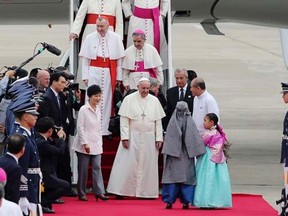Pope Francis (C) is escorted by South Korean President Park Geun-hye upon his arrival at Seoul Air Base in Seongnam August 14, 2014.   REUTERS/Ahn Young-joon/Pool
