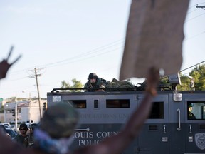 A police officer aims his weapon at a demonstrator protesting the shooting death of teenager Michael Brown, in Ferguson, Missouri August 13, 2014. (REUTERS/Mario Anzuoni)