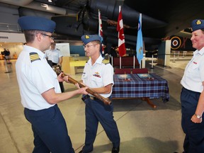 Commanding officer (CO) of 8 Wing/CFB Trenton, Ont. passes 8 Air Maintenance Squadron's hand-carved mace from the unit's outgoing CO Lt. Col. Tressa Home to incoming CO Lt. Col. Andrew Wedgwood during a change of command ceremony held at National Air Force Museum of Canada in Trenton, Ont. Thursday, Aug. 14, 2014.    - Jerome Lessard/The Intelligencer.