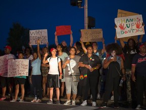 People hold signs during a peaceful demonstration, as communities react to the shooting of Michael Brown in Ferguson, Missouri August 14,  2014.   REUTERS/Mario Anzuoni