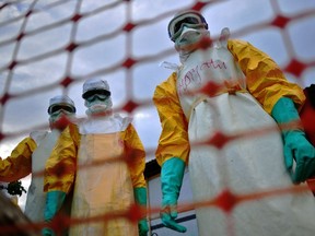 Medecins Sans Frontieres (MSF) medical staff wearing protective clothing treat the body of an Ebola victim at their facility in Kailahun, on Aug. 14, 2014. (AFP PHOTO/Carl de Souza)