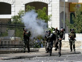 Israeli security forces fire tear gas towards Palestinian stone throwers (unseen) during clashes following a rally to support people in the Gaza Strip on Aug. 15, 2014 at the entrance of the West Bank city of Bethlehem, following weeks of fighting between Israel and Hamas. (AFP PHOTO/MUSA AL-SHAER)