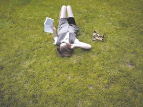 A woman lies in the grass while reading a book, at Columbia University in New York earlier this year. Londoner William Oost says more of us should follow her lead and enjoy the grass and the dwindling days of beloved summer. (Carlo Allegri/Reuters)
