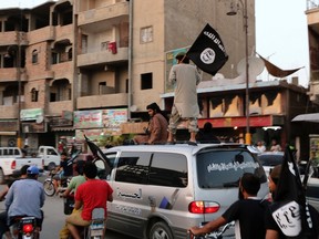 Members loyal to the Islamic State in Iraq and the Levant (ISIL) wave ISIL flags as they drive around Raqqa June 29, 2014. (REUTERS/Stringer)