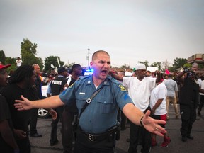 A Missouri State Highway Patrol officer yells for people to move back as they evacuate a woman who needed medical help during a peaceful demonstration, as communities react to the shooting of Michael Brown in Ferguson, Missouri August 14, 2014. (REUTERS/Lucas Jackson)