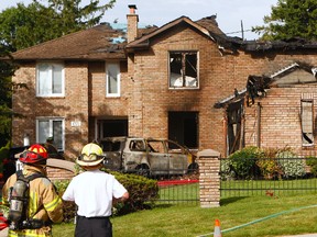 An early morning blaze erupted on Rougemount Dr., just north of Kingston Rd., Saturday destroying much of the home and two vehicles. Pickering firefighters survey the damage as crews continued to battle hot spots throughout the morning. (CHRIS DOUCETTE/TORONTO SUN)