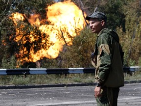 An armed pro-Russian separatist looks as flames erupt from a gas pipeline after a shelling in Donetsk, August 15, 2014. EUTERS/Sergei Karpukhin