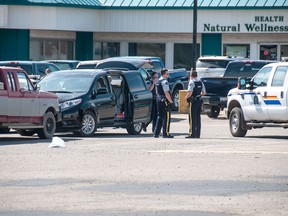 Police collect evidence in the IGA parking lot after a child was left in a van while its mother shopped. Temperatures were over 30 degrees celsius in Whitecourt. Bryan Passifiume photo | QMI Agency