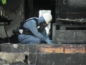 An investigator with the Ontario Fire Marshal's Office on Sunday, Aug. 17, 2014 probes the charred townhouse that exploded Friday night. John Miner/The London Free Press