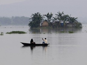 Indian villagers paddle a boat through floodwaters near partially-submerged houses in Balimukh village in the Morigaon district of Assam state on August 17, 2014. Heavy downpours in India have triggered landslides and flooding that have claimed at least 24 lives since August 15, 2014, according to government officials. Hundreds of people die every year in floods and landslides during the monsoon season in South Asia. While annual rains are a lifeline for the region's farmers, flooding, landslides and building collapses are frequent during the monsoon season, which lasts from June to September.  AFP PHOTO / Biju Boro
