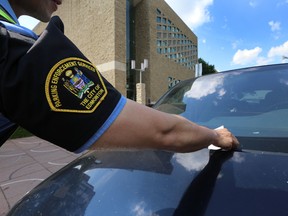 A parking enforcement officer places a ticket on a vehicle near city hall. Edmonton’s 3,300 parking meters will soon be replaced  with new technology.  City council committee voted Wednesday to replace them during council meetings at city hall in Edmonton, Alta., on Monday, June 30, 2014.  Perry Mah/Edmonton Sun/QMI Agency