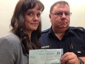 Manitoulin OPP Det.-Const. Patty Smith and Const. Al Boyd with Stan Richards' unclaimed paycheque. (MIKE STROBEL, Toronto Sun)
