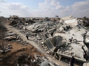 A Palestinian woman walks past the ruins of houses which witnesses said were destroyed during the Israeli offensive in Johr El-Deek village near the central Gaza Strip Aug. 17, 2014.  REUTERS/Ibraheem Abu Mustafa