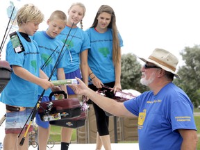 Adam, a little brother in the Big Brothers, Big Sisters program, gets awarded a box of tackle by Tom Beaton, right, co-chair of the Mitchell's Bay Open Bass Tournament. Ten youth involved with the program were taken out on a fishing charter Saturday for the day and given new rods, reels, and tackle boxes as part of the tournament's mandate to give back to the community. Diana Martin/Chatham Daily News/QMI Agency