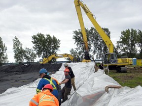 Crews with Great Lakes Offshore Services, struggle to get plastic sheeting secured in the main containment bin that holds dredged material from the dredging operation at the new Quinte Marina Thursday, August 14, 2014. The marina is set to open in late spring 2014. Ernst Kuglin/The Intelligencer/QMI Agency