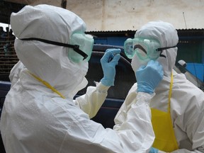 Health workers wearing protective clothing prepare themselves before carrying an abandoned dead body presenting Ebola symptoms at Duwala market in Monrovia on August 17, 2014. (REUTERS/2Tango)
