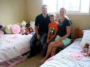 (From left) Terry Willoughby, Kyan Willoughby and Dallas Willoughby sit in an empty bedroom that belongs to the two girls who were adopted by the family a year ago. The bedroom with two single beds for the girls and their toys is ready but the girls are still in their birth country, the Democratic Republic of the Congo.