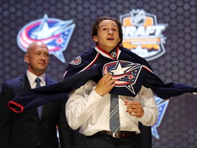 Sonny Milano puts on a team sweater after being selected as the number sixteen overall pick to the Columbus Blue Jackets in the first round of the 2014 NHL Draft at Wells Fargo Center on Jun 27, 2014 in Philadelphia, PA, USA. (Bill Streicher/USA TODAY Sports)