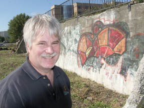 David Dossett, standing in front of the concrete support he was about to paint as part of the On The Wall mural project, wants more people to think locally when it comes to buying artwork. (Michael Lea/The Whig-Standard)