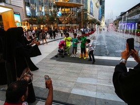 Tourists take photos of their children in front of Siam Paragon Department Store in central Bangkok Dec. 16, 2013.  REUTERS/Athit Perawongmetha