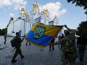 Members of Ukrainian self-defence battalion "Donbas" carry their battalion's flag to be blessed in a ceremony in Mikhailovsky Cathedral in Kiev August 19, 2014. (REUTERS/Gleb Garanich)