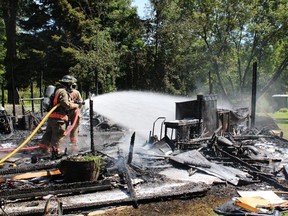A Belleville, Ont. firefighter hoses down the remains of a residential garage at 450 Harmony Rd., east of Foxboro, Ont., after a fire broke out there Monday afternoon, Aug. 18, 2014. - Photo by Dave MacMullen, Fire Prevention Officer with Belleville Fire Department.