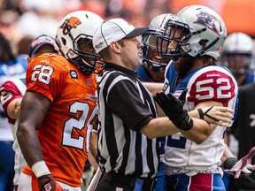 A referee separates Lions player Jamall Johnson (left) and  Alouettes player Nicolas Boulay (right) during CFL action in Vancouver on July 19, 2014. (Carmine Marinelli/QMI Agency)