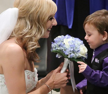Hunter Wolfe Melnyk, 2, comes over to smell his mother's wedding bouquet during the wedding ceremony. Megan Wolfe, 28, and Josh Melynk were married during a ceremony at the Union Bank Inn, 10053 Jasper Ave., in Edmonton Alta., on Wednesday Aug. 20, 2014. Wolfe has stage 4 stomach cancer. The couple turned to crowdfunding to make the wedding a reality. The couple has two year-old twin boys. Wolfe also has two other sons aged 6 and 7. Melynk also has an eleven year-old daughter. David Bloom/Edmonton Sun/QMI Agency