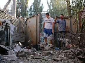 People walk in front of a building damaged by, what locals say, was recent shelling by Ukrainian forces in Donetsk August 20, 2014.  REUTERS/Maxim Shemetov