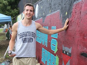 Mikhail Peabody stands in front of the artwork he created for On The Wall, a week-long street art festival that allows artists to cover a retaining wall on the Wellington Street extension with their work. FRI., AUG 22, 2014 KINGSTON, ONT. MICHAEL LEA\THE WHIG STANDARD\QMI AGENCY