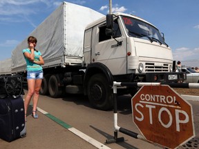 Trucks of a Russian convoy carrying humanitarian aid for Ukraine drive onto the territory of a Russia-Ukraine border crossing point "Donetsk", as a woman waits for her son who has fled from fighting in eastern regions of Ukraine and is expected to cross the border, in Russia's Rostov Region, August 22, 2014. Ukraine declared on Friday that Russia had launched a "direct invasion" of its territory after Moscow sent a convoy of aid trucks across the border into eastern Ukraine where pro-Russian rebels are fighting government forces. REUTERS/Alexander Demianchuk