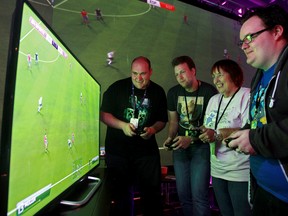 (left to right) The Edmonton Sun's Matt Dykstra and other Extra Life volunteers Ryan Koesling, Maggy Carter, and Justin Livingston play Fifa14 at the Extra Life stage in the Edmonton Expo Centre Hall B, during K-Days, in Edmonton Alta., on Wednesday July 23, 2014. Extra Life Edmonton has been hosting video game tournaments during K-Days to raise awareness about their Oct. 25  24-hour video game marathon fund-raiser for the Stollery children's Hospital Foundation. David Bloom/Edmonton Sun/ QMI Agency