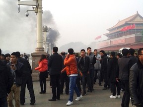 People walk along the sidewalk of Chang'an Avenue as smoke rises in front of the main entrance of the Forbidden City at Tiananmen Square in Beijing in this October 28, 2013 file photo. China has executed eight people for "terrorist" attacks in its restive far western region of Xinjiang, including three who "masterminded" a dramatic car crash in the capital's Tiananmen Square in 2013, state media said. REUTERS/Stringer/Files