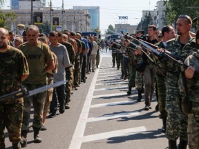 Armed pro-Russian separatists (R) escort a column of Ukrainian prisoners of war as they walk across the centre of Donetsk August 24, 2014. Pro-Russian separatist rebels force-marched dozens of Ukrainian prisoners of war along the main street of the rebel-held Ukrainian town of Donetsk on Sunday. REUTERS/Maxim Shemetov